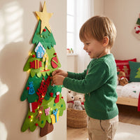 Niño colocando un adorno de jengibre en el árbol de Navidad de fieltro