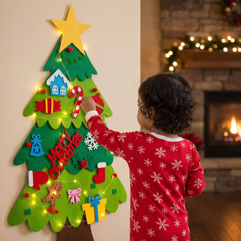 Niña con pijama de copos decorando el árbol de fieltro con luces