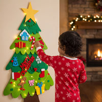 Niña con pijama de copos decorando el árbol de fieltro con luces